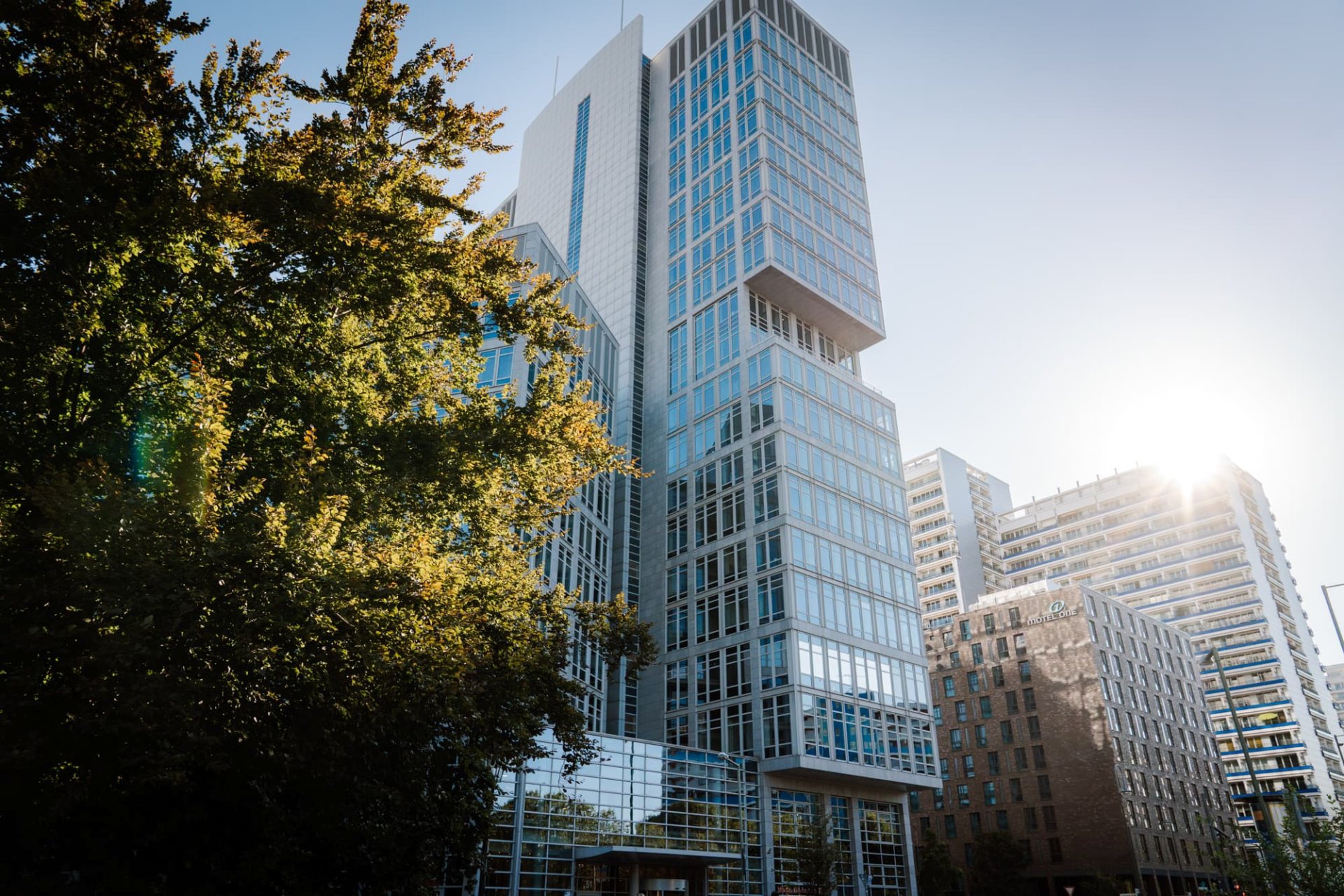 Tall office building seen from from the outside, with a tree in front of it.