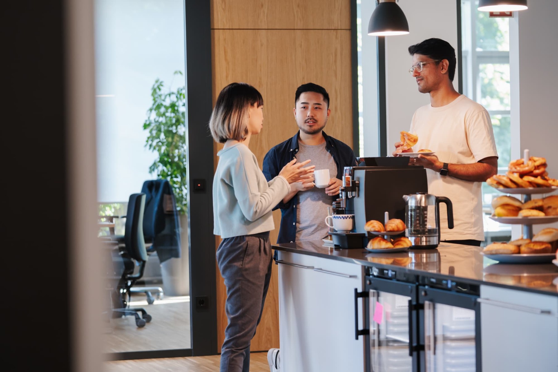 Three employees taking a break around the coffee machine